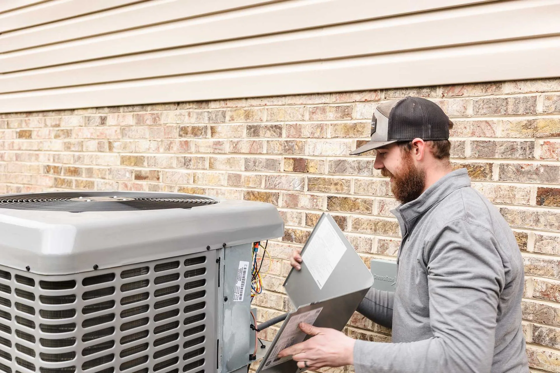 Lucas checking an outdoor air conditioner with a laptop