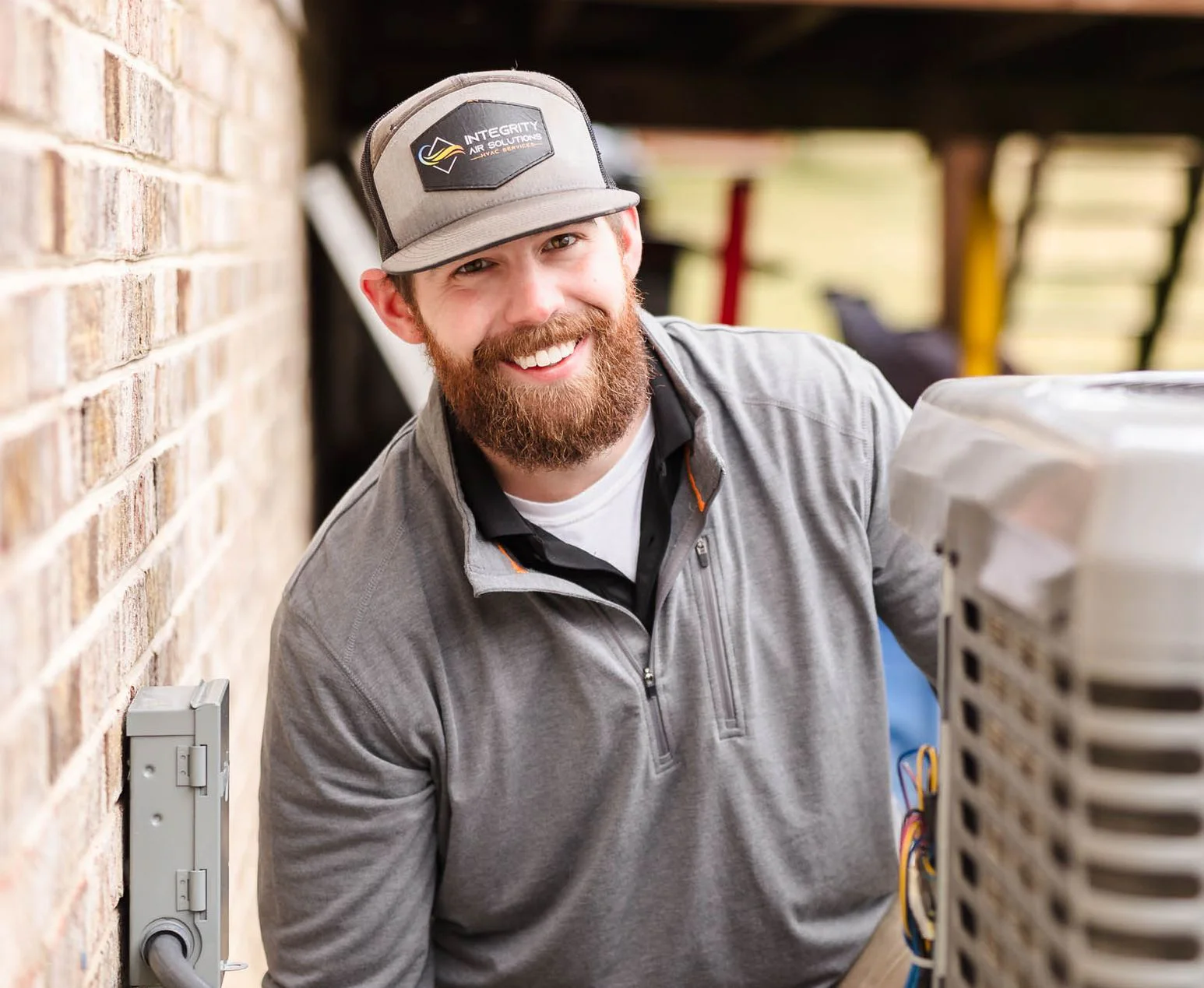 Lucas of Integrity Air Solutions smiling beside an air conditioner